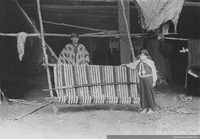 Niña y joven mapuche junto a un telar