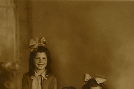 Una niña de pie y las otras dos niñitas sentadas en un sillón, 1925