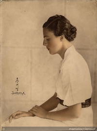 Mujer posando sentada y de perfil, de pelo corto ondulado y vestido blanco con cinturón, entre 1930 y 1940
