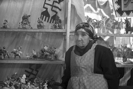 Mujer mapuche junto a artesanías de greda